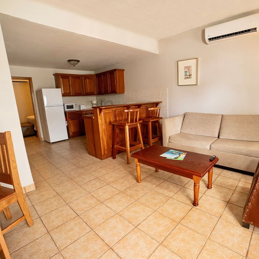 A cozy living area featuring a kitchen bar, a couch, and a wooden coffee table.