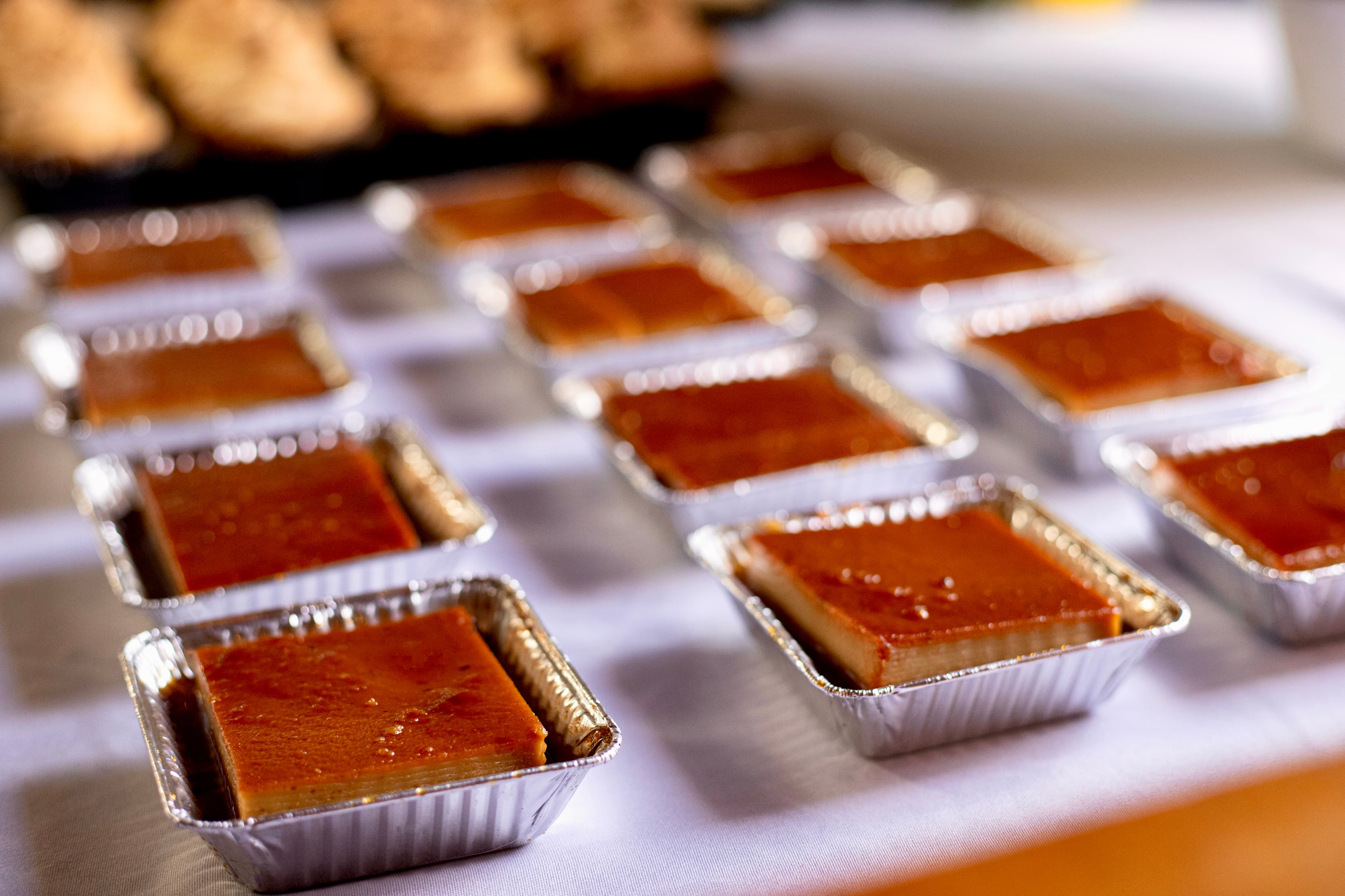 A series of small, rectangular desserts in foil pans are arranged on a table.