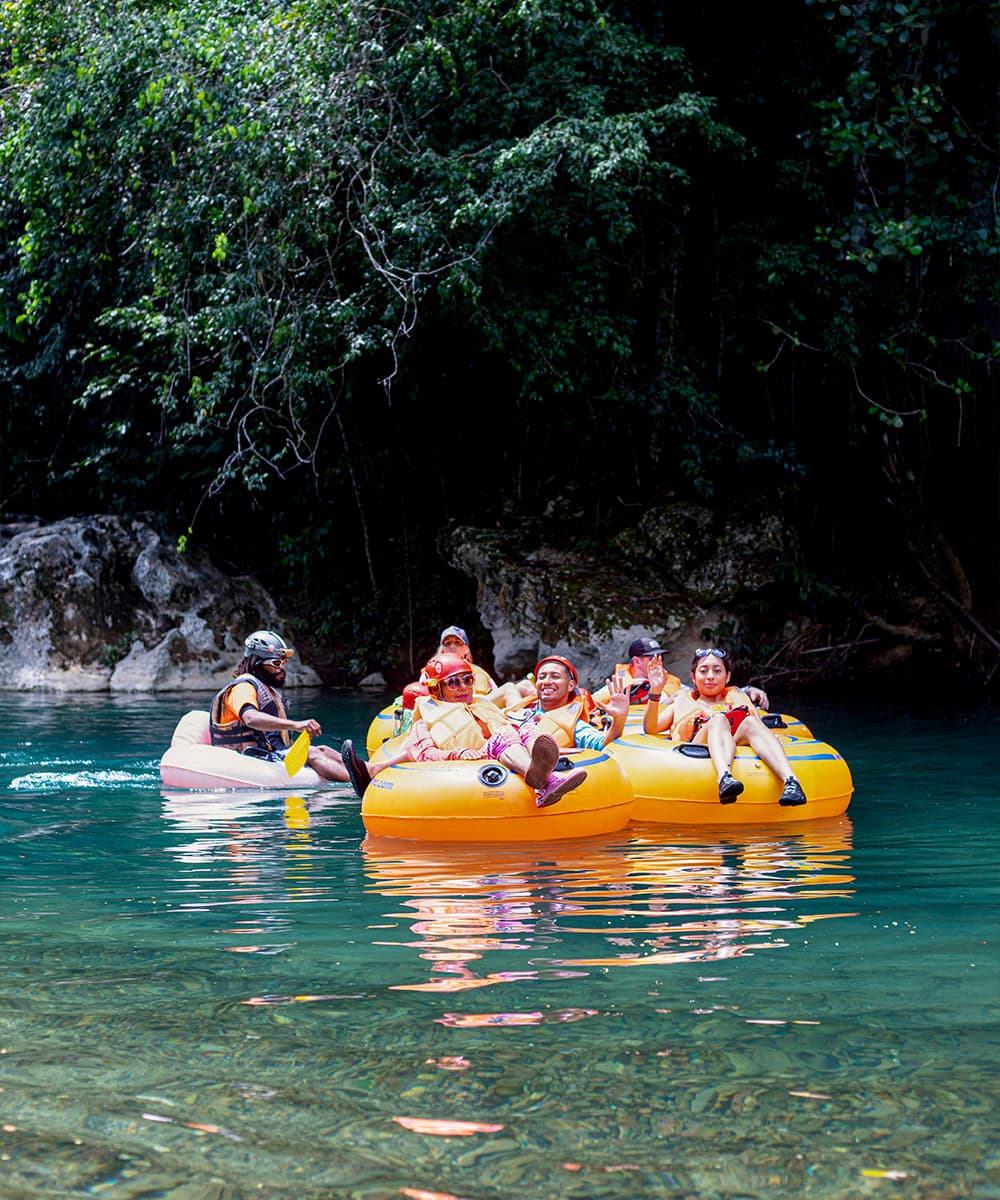 A group of people in colorful inflatable rafts enjoying a serene river surrounded by lush greenery.